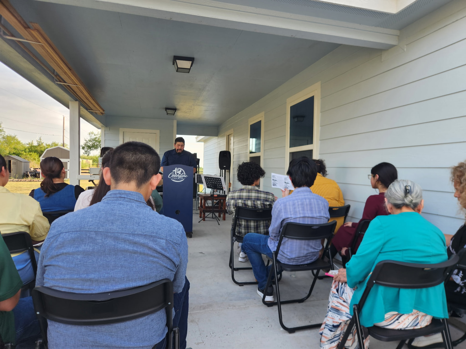 Pastor preaching to the church family on the porch during a Sunday evening service in Lyford, Texas